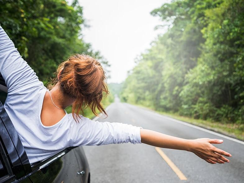 Girl spreading her arms out the window of a car