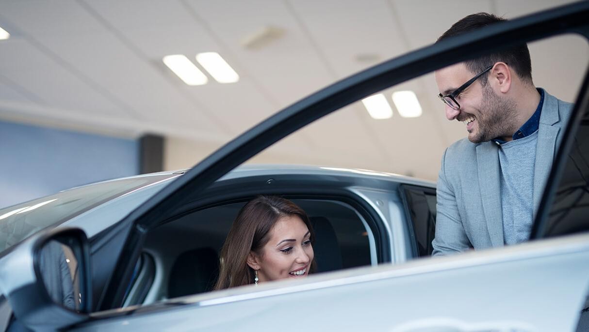 Dealership sales associate showing a customer a new vehicle