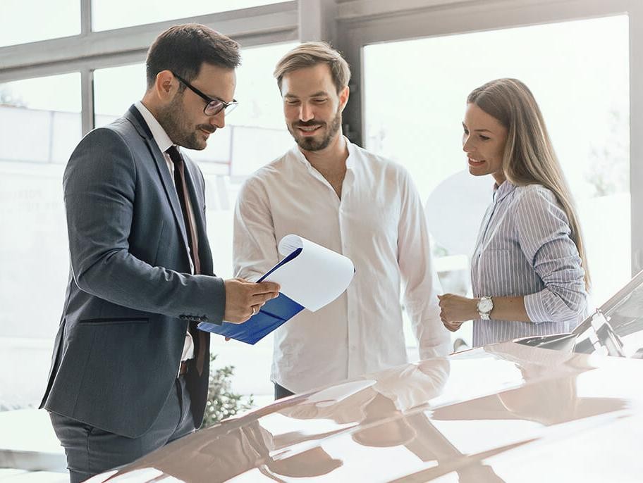 Dealership sales associate helping a smiling couple shop for a new vehicle