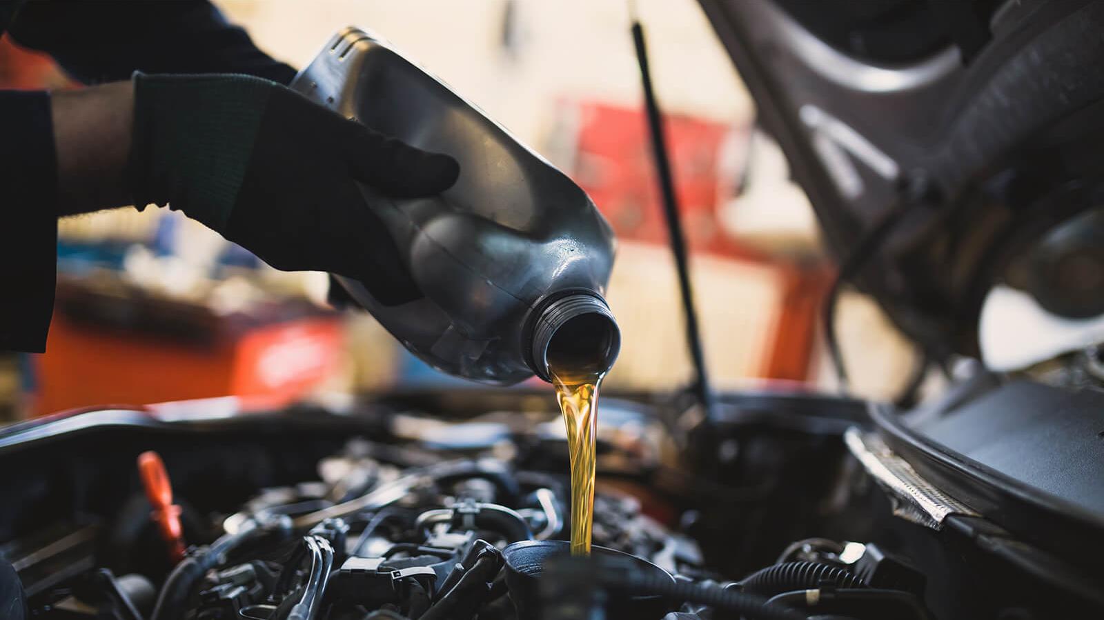 Service mechanic adding engine oil to a vehicle