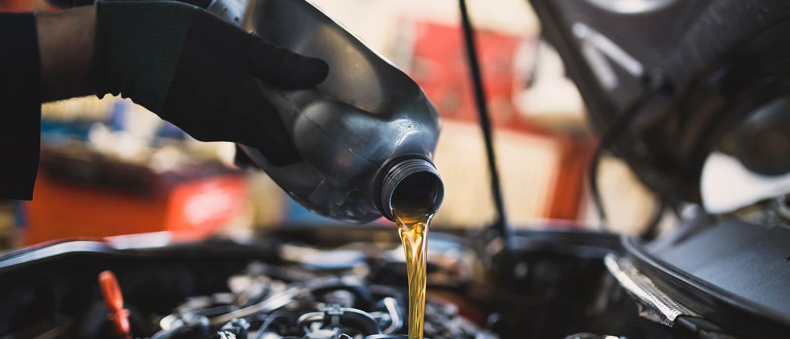 Service mechanic adding engine oil to a vehicle