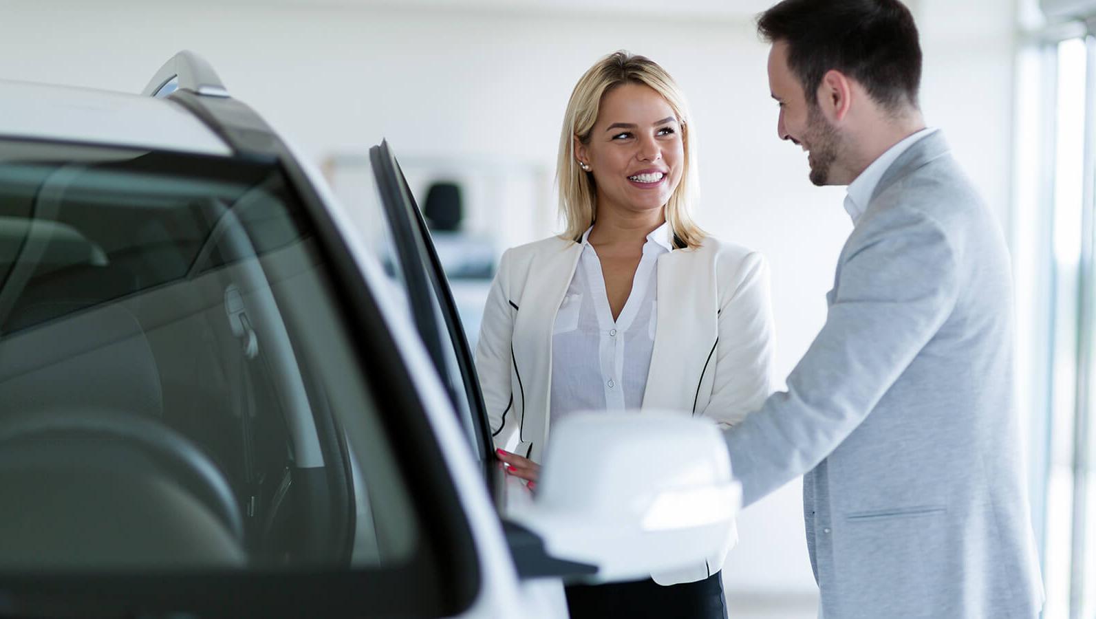 Dealership sales associate showing a customer a new vehicle