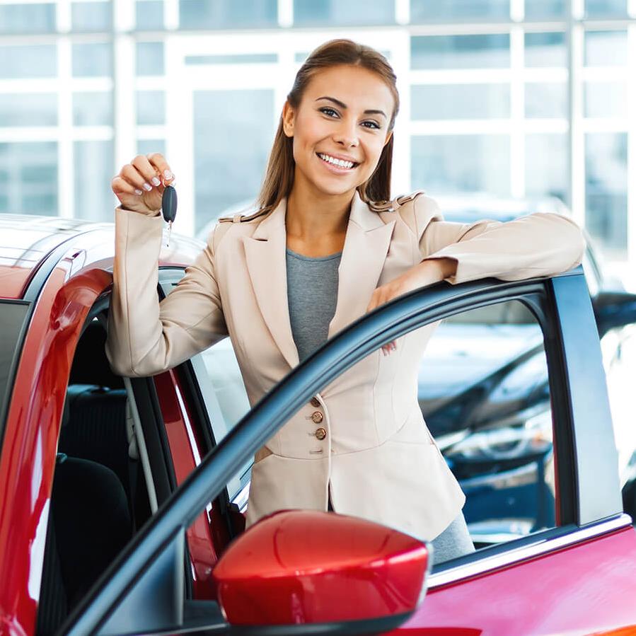 Smiling woman holding keys by a new car Smiling woman holding keys by a new car