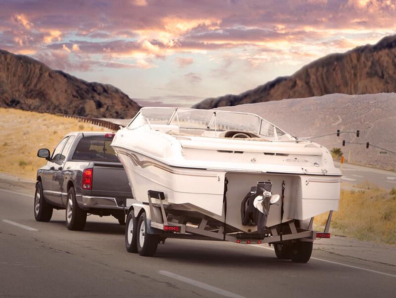 Truck towing a boat, on a rural road driving towards the sunset Truck towing a boat, on a rural road driving towards the sunset