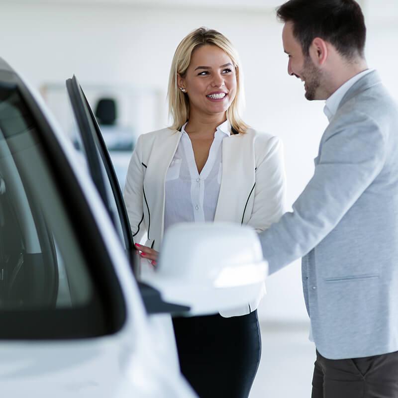 Dealership sales associate showing a customer a new car