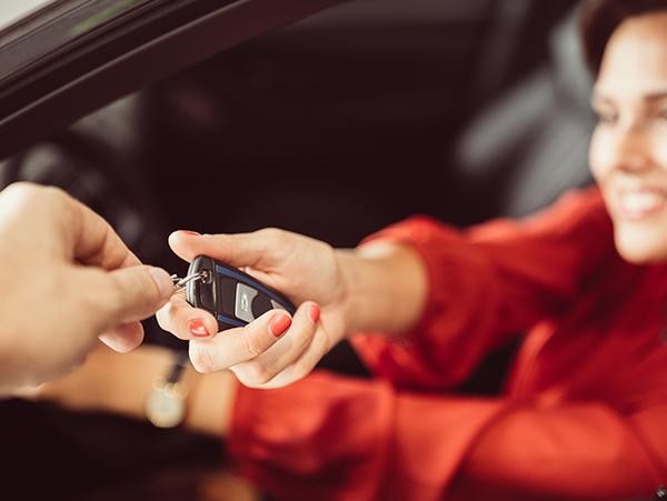 Woman in red taking her new car keys