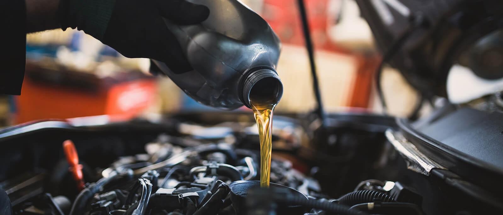 Service mechanic adding engine oil to a vehicle