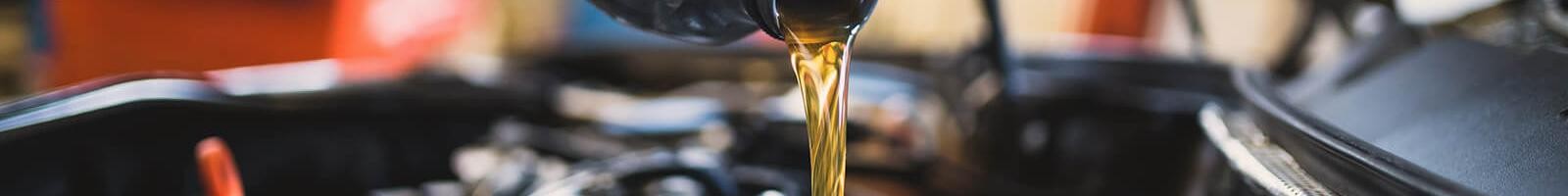 Service mechanic adding engine oil to a vehicle