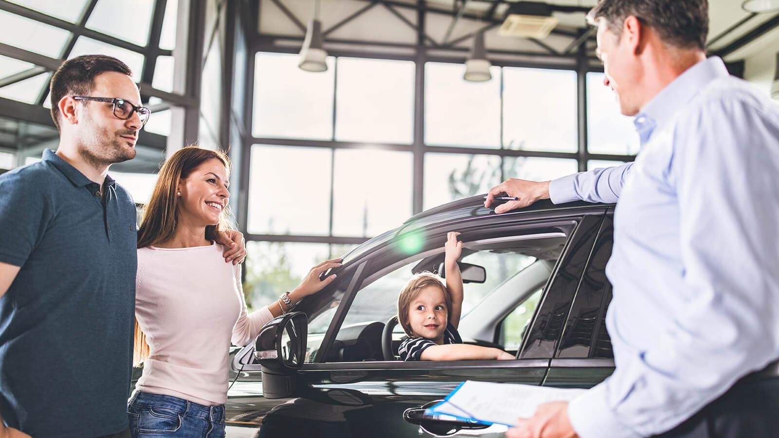 Smiling young family shopping for a new car