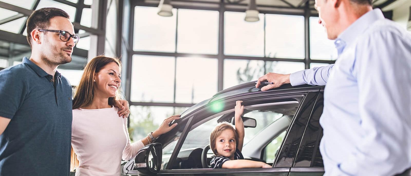 Smiling young family shopping for a new car