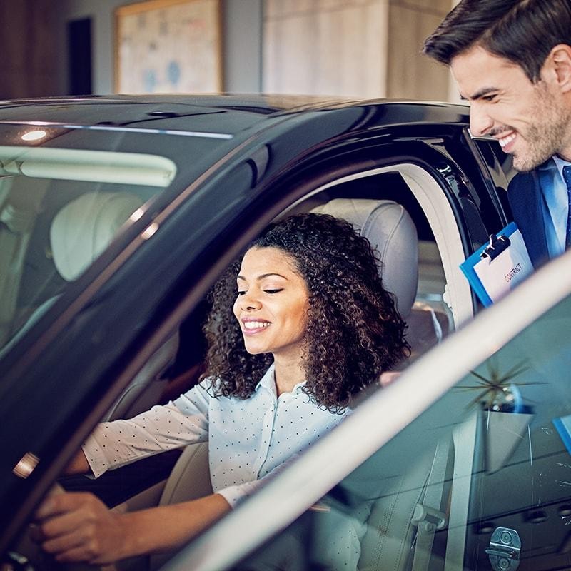Woman in a dealership sitting in a new vehicle