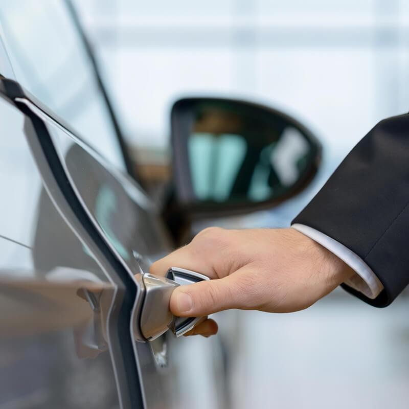 Man holding the door handle of a vehicle