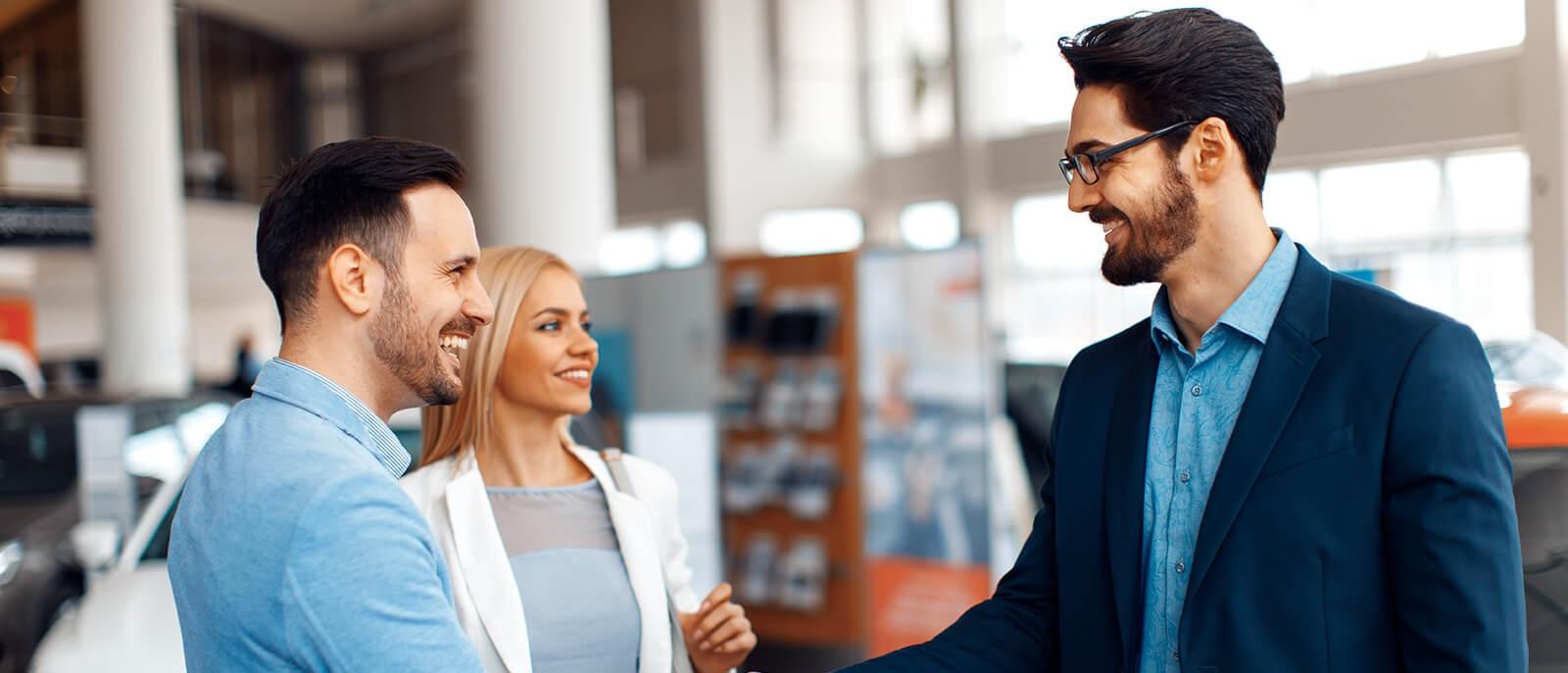 Couple shaking hands with a dealership sales associate