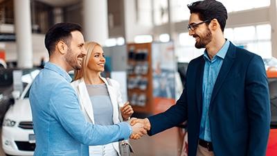 Couple shaking hands with a dealership associate