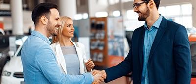 Couple shaking hands with a dealership associate