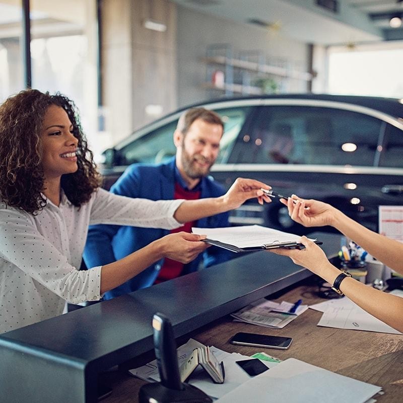 Couple signing finance documents in a dealership