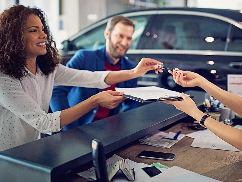 Couple signing finance documents in a dealership