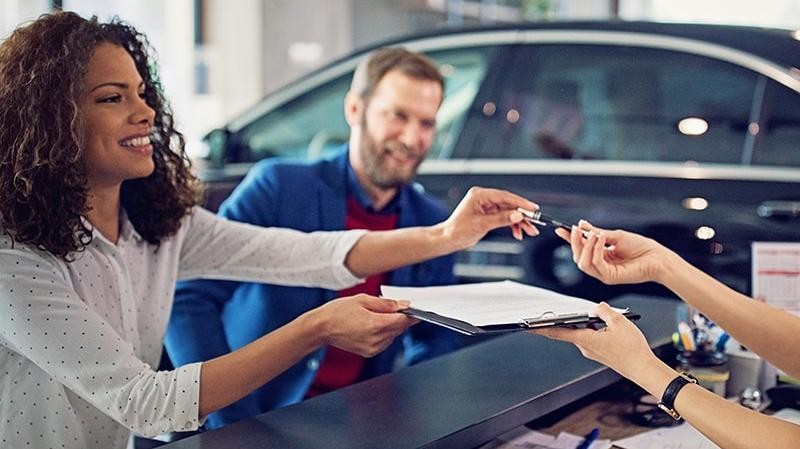 Couple signing finance documents in a dealership