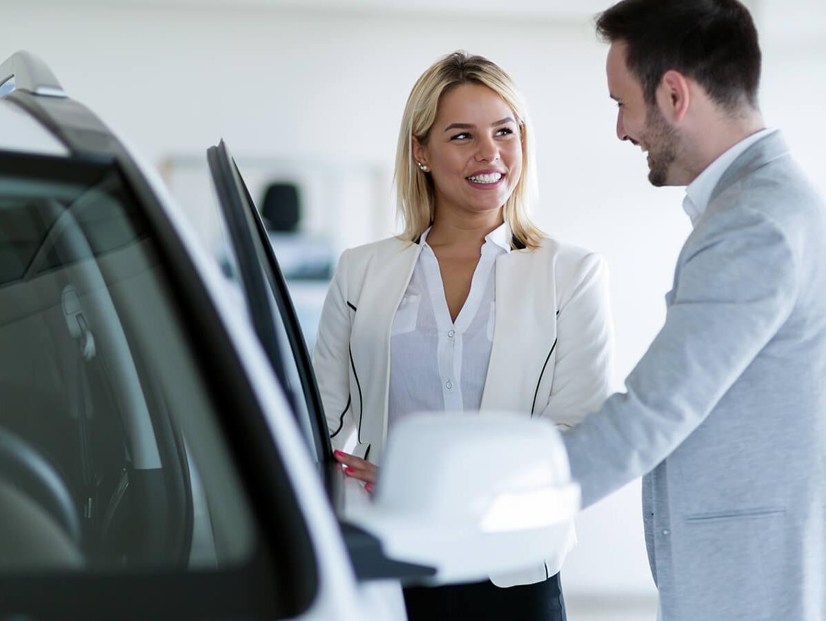 Dealership sales associate showing a customer a new vehicle