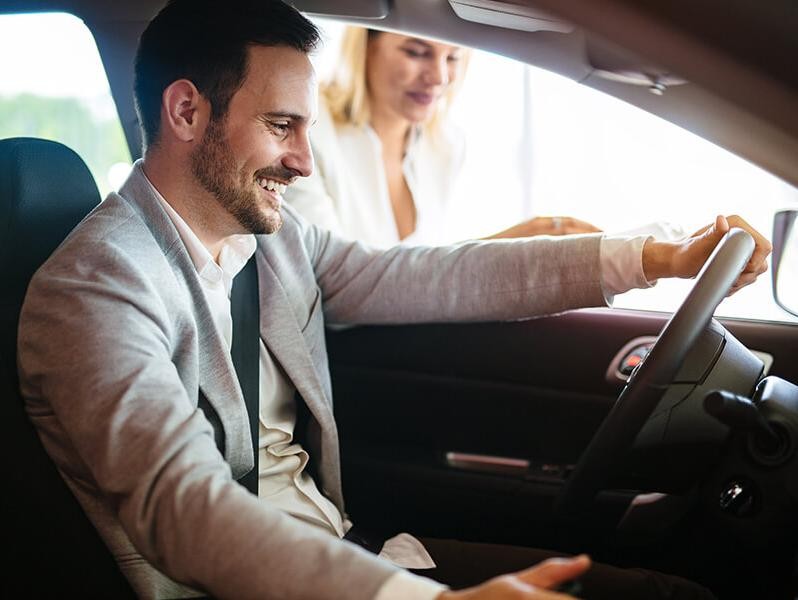 Man sitting in a car in a dealership showroom