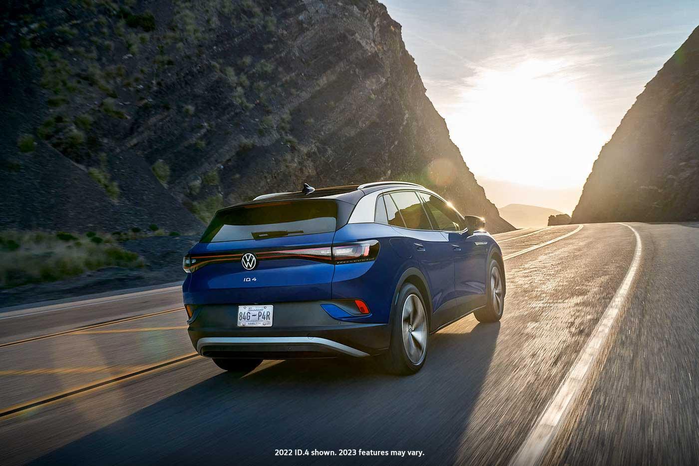 A rear view of an ID.4 in Dusk Blue Metallic, driving along a mountain road.