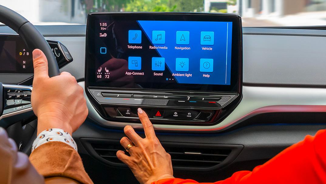 A close-up shot of a woman’s hand touching the ID.4 available 12" touchscreen display.