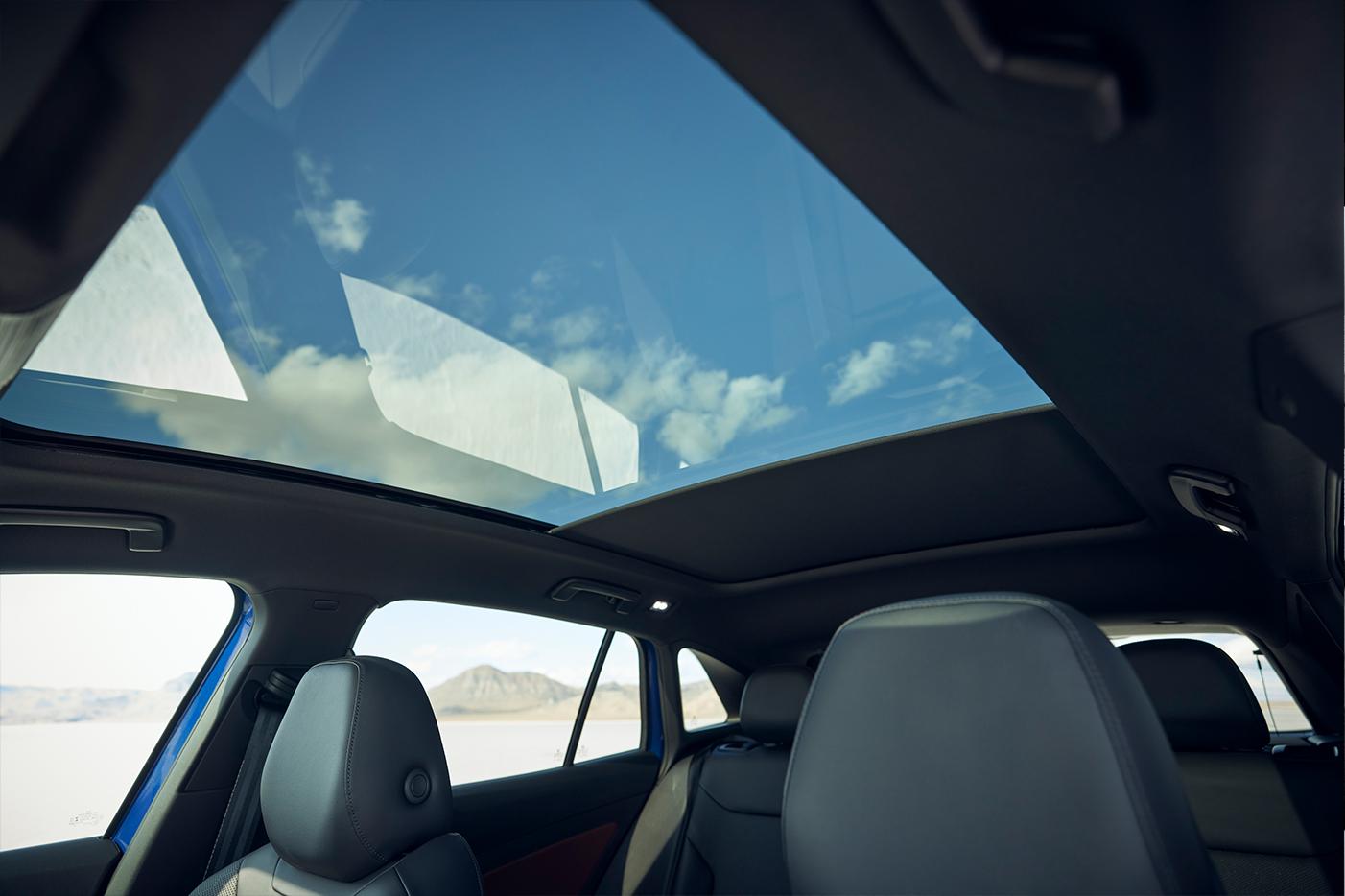 Interior shot of an ID.4 with focus on the glass roof, sunshade, passenger side windows, and front seat headrests.
