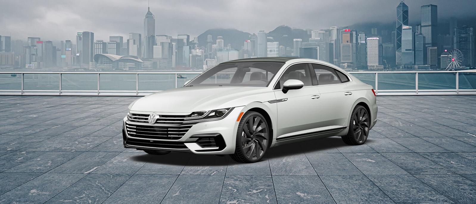 A white Arteon parked, sea and buildeings in the background A white Arteon parked, sea and buildeings in the background