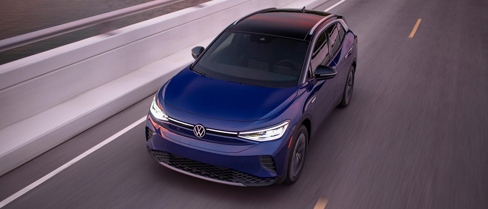 A blue Volkswagen ID.4 electric vehicle driving down the highway. A blue Volkswagen ID.4 electric vehicle driving down the highway.