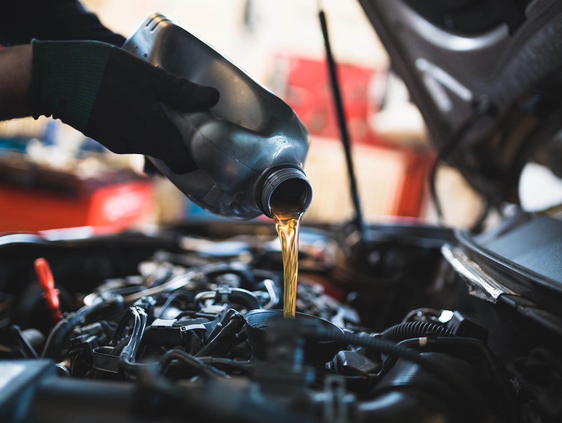 Technician pouring oil into engine
