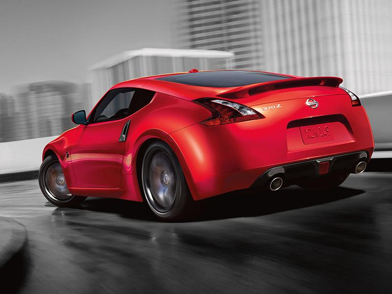 Rear view of a red Nissan 370Z Coupe driving along a city highway.