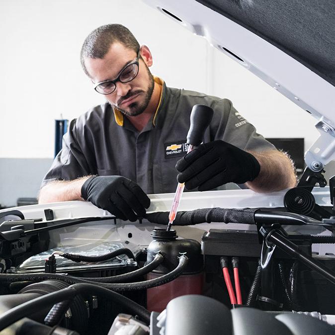 Service technician working under the hood of a car.