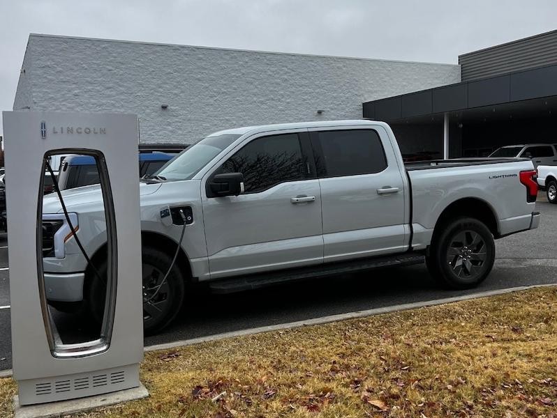Silver Ford F-150 Lightning at charging station at car dealership
