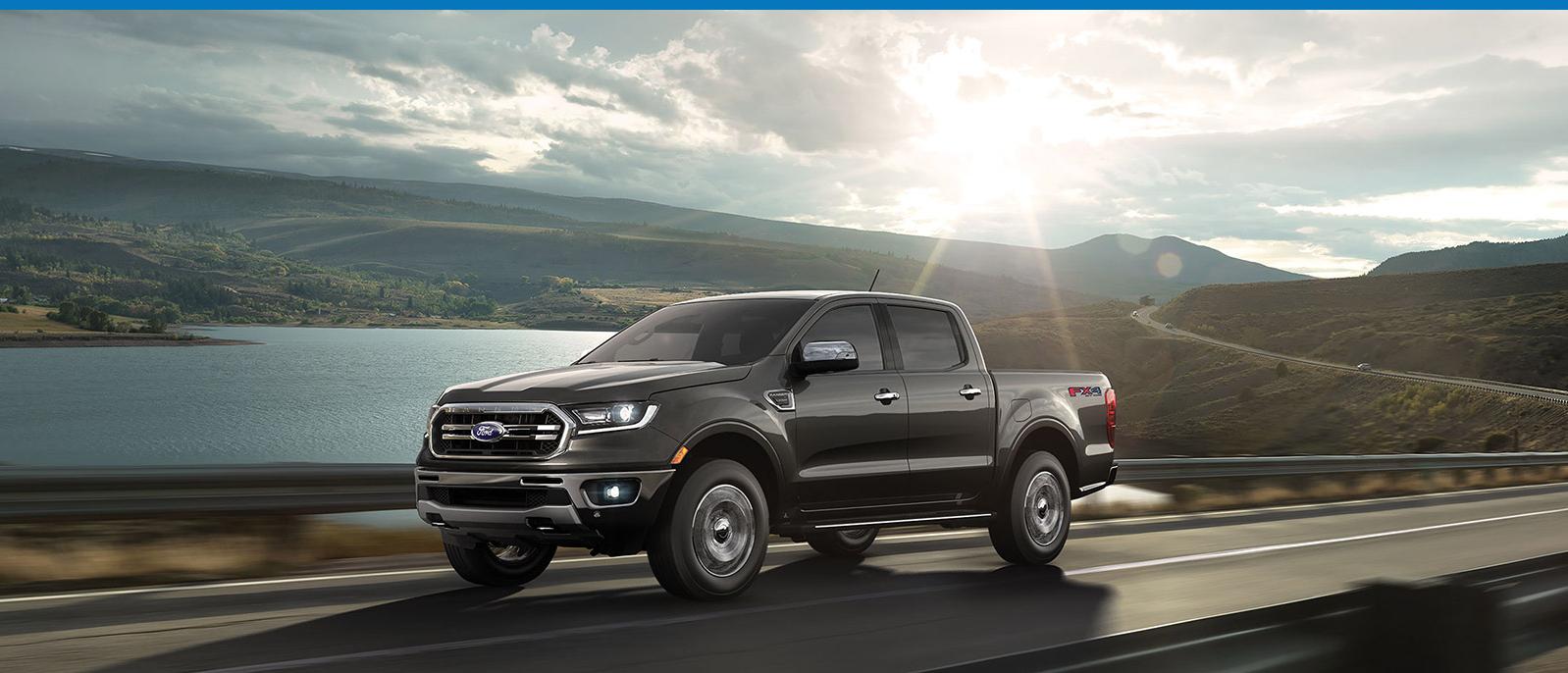 2020 Ranger driving on road near a lake with rolling prairies in the background.