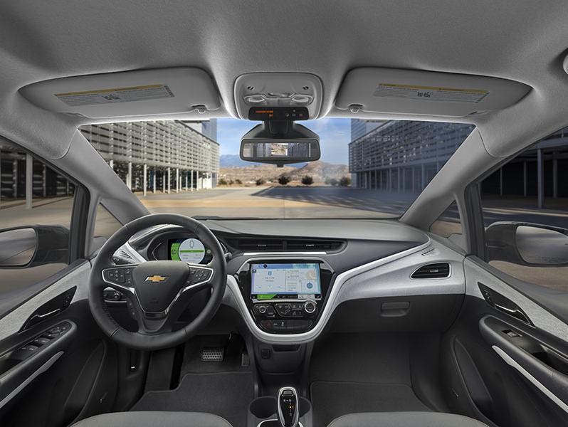 The Interior of a Chevrolet bolt looking out the windshield from the drivers position. Facing the steering wheel and center control panel with screen.