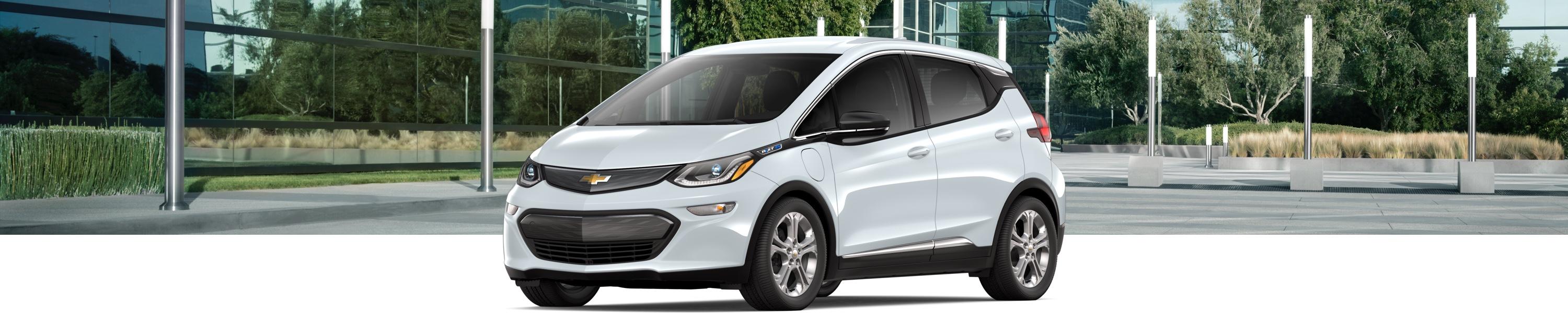 A Chevrolet bolt parked with a city background behind it.