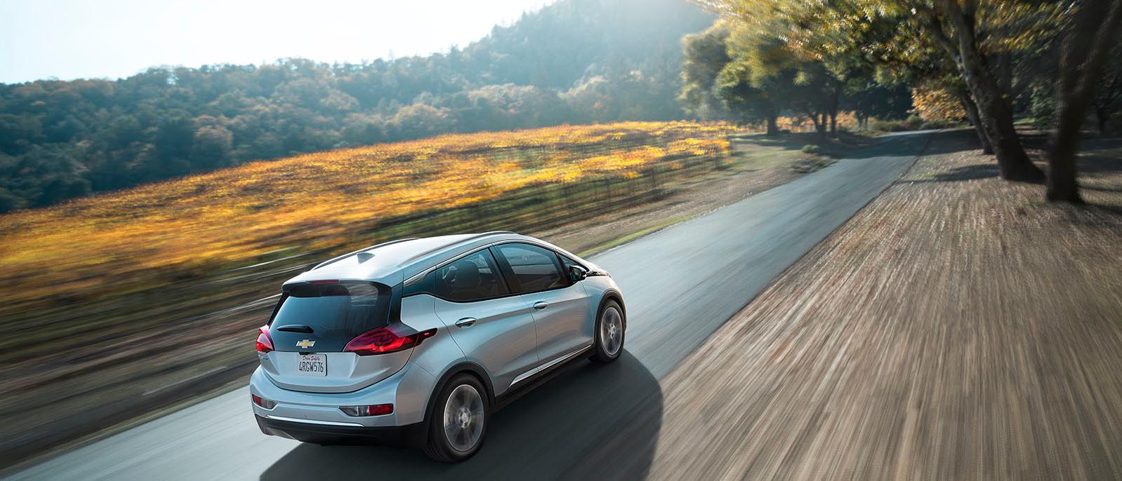 Chevy Bolt driving on a road in a forested area