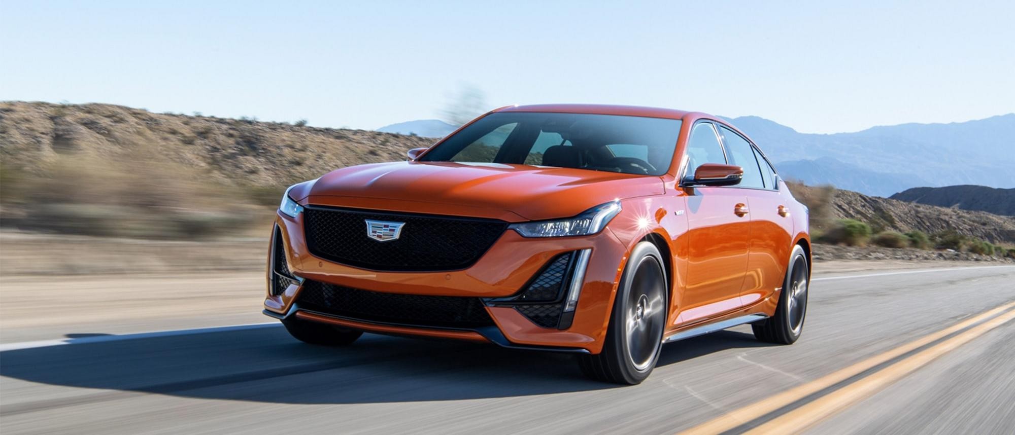 Orange 2023 Cadillac CT5-V driving on road through desert