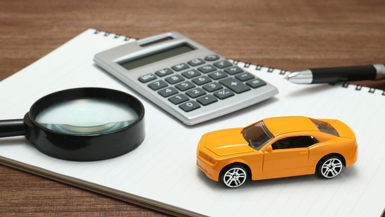 Toy car, magnifying glass, calculator, pen and notebook
