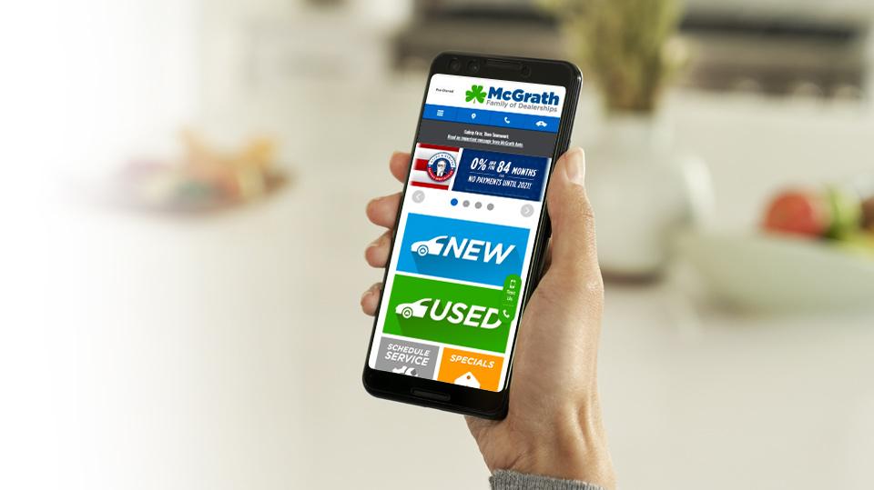 Hand holding Iphone with McGrath Auto web page showing on screen Hand holding Iphone with McGrath Auto web page showing on screen