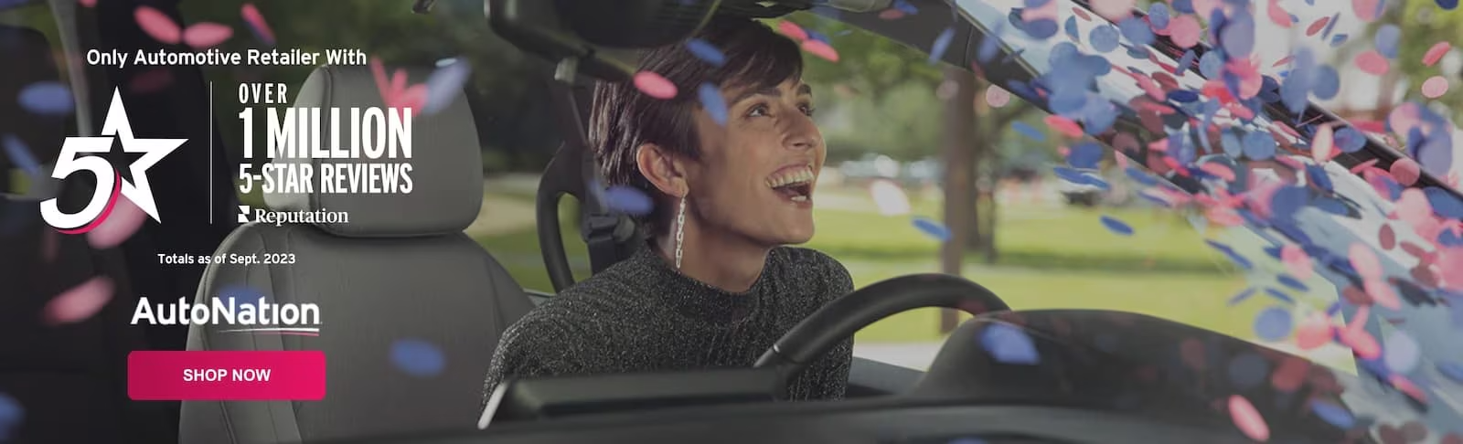 A woman sitting in the driver's seat of a car looking delighted at confetti falling on her windshield