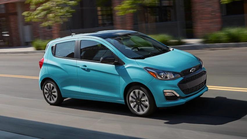An aqua colored 2022 Chevrolet Spark driving down a road