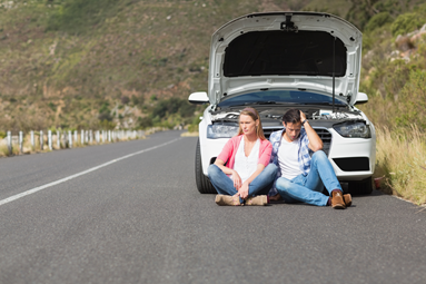 car broken down and two people sitting on road