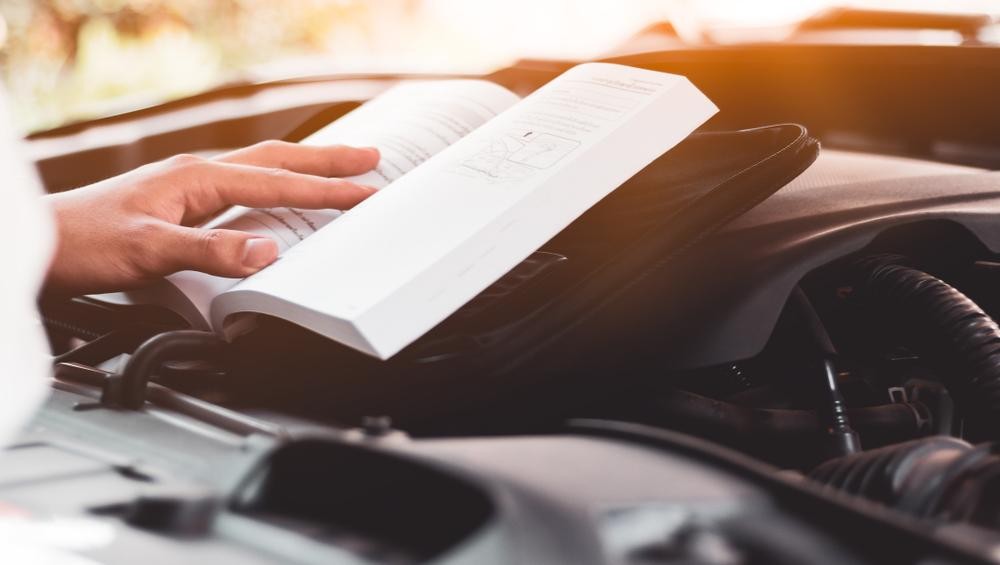 person reading an instruction manual for car person reading an instruction manual for car