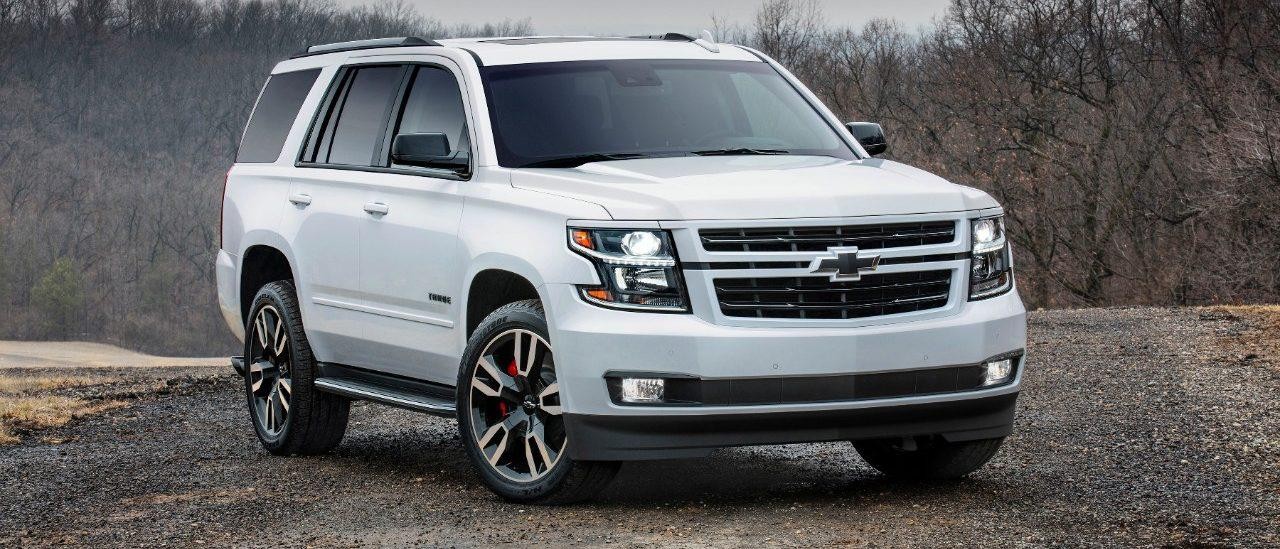 White Chevy Tahoe parked in a woody area