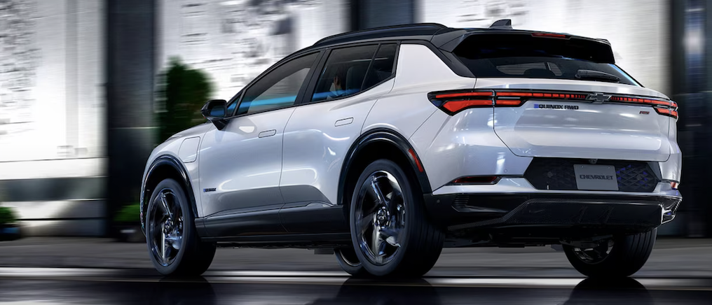 rear angled view of a white Chevy Equinox driving