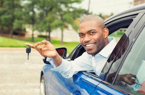 African American man holding keys and leaning out of his car window