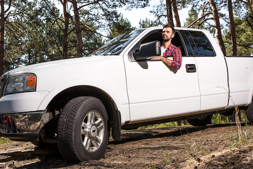 man looking out of his truck in the woods