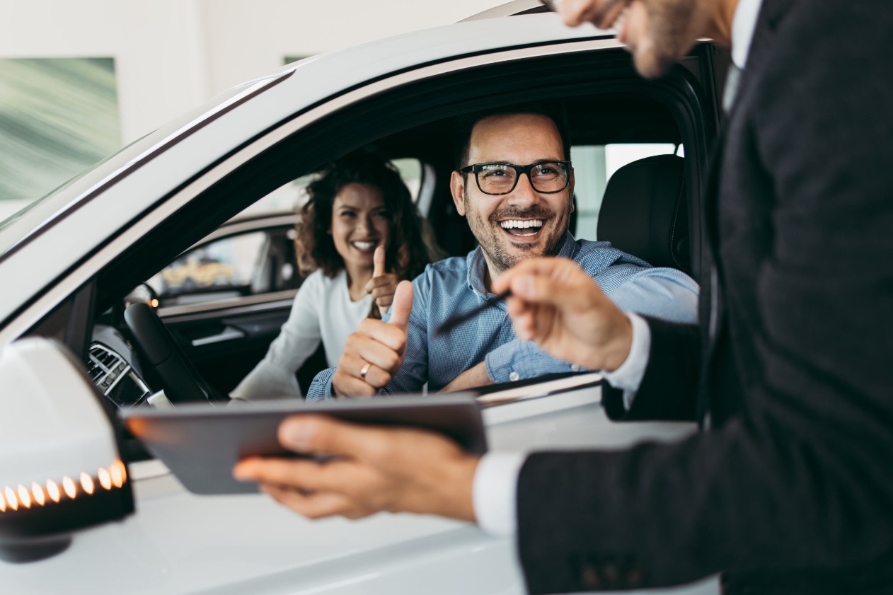 Young couple leaning against a new car