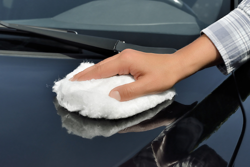 person's hand holding a cloth on hood of car